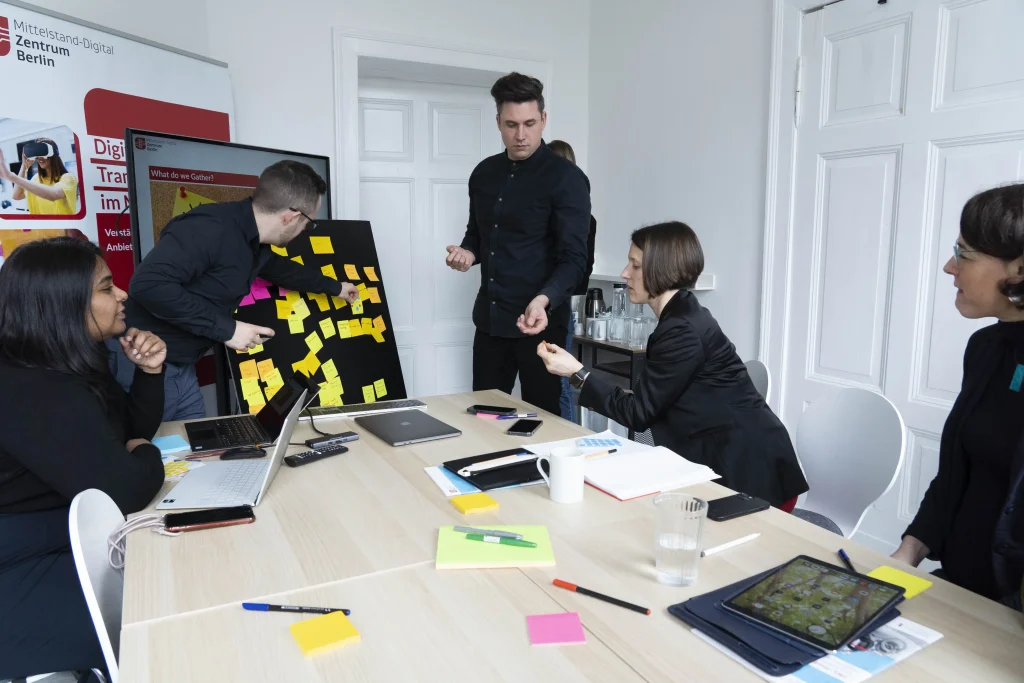 Workshop-Teilnehmende arbeiten an einem Board und ordnen Post-Its